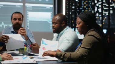 Çalışma saatleri dışında yapılan bir iş toplantısında dosya analizi, bilgi alışverişi ve performans ölçümleri için proje gündemi planlamasına katılacaklar. Geç saate kadar brifing. Kamera B.