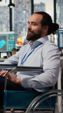 ArGe ofisinde belden aşağısı felçli bir adam yeşil teknoloji güneş panelleri tasarlıyor. Tekerlekli sandalyedeki engelli çalışanlar güneş pillerini, temiz enerji üretimini ve kamera B 'yi geliştirmek için simülasyon çalıştırıyorlar.