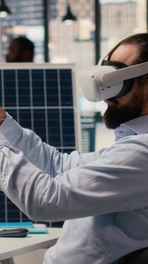 Sürdürülebilirlik uzmanı gelişmiş güneş panelleri tasarlamak için VR kulaklık kullanır. İşçi güneş pillerini geliştirmek için sanal gerçeklik simülasyonu çalıştırıyor, yeşil enerjinin benimsenmesini hızlandırıyor, kamera B