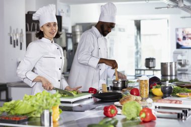 Profesyonel bir mutfakta, şef kesme tahtaları ve doğrama malzemeleri kullanarak gurme yemekleri hazırlıyor. Taze ürünlerle yemek pişirme, lezzetli yemekler için yemek hazırlama, gastronomi.