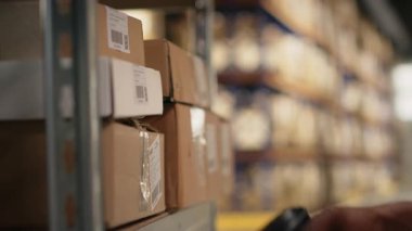 Endüstriyel raflardaki kargo etiketlerini işlemek için barkod tarayıcısı kullanan siyahi işçilere yaklaş. Paket izleme servisi için takip bilgileri ve lojistik bilgileri taranıyor. Kamera B.