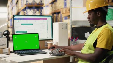 İthalat ihracat detaylarıyla ilgilenen erkek çalışan. Ekranda fotokopi alanı var. Depo masasında çelik yelek ve kask giyiyor. Personel izleme paketi yazılım takibi. Kamera B.