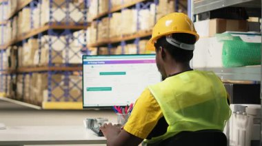 Genç adam barkodlarda tarayıcı kullanıyor ve dağıtım merkezine etiket takıyor. Organize raflar, paket etiketleri ve güzergah planlaması verimli sevkiyat ve sipariş yerine getirilmesi. Kamera B.