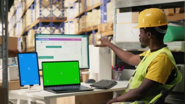 Kopya alanının yanındaki sevkiyatları takip eden Afrikalı Amerikalı işçiler, organize raflar ve paletler ile depo operasyonları. Doğru lojistik ve tam zamanında sipariş. Kamera B.