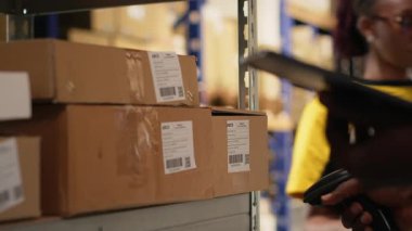 Delikanlı, barkod etiketlerinde tarayıcı kullanıyor. Organize raf, paket etiketleri ve güzergah planlaması verimli dağıtım ve sevkiyat desteği. Lojistik merkezi. Kamera B.