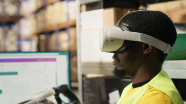 Kara depo memuru sanal gerçeklik kulaklığını online alışveriş siparişleri için kullanıyor, envanterden kargo malları hazırlıyor ve bilgisayar yazılımındaki paket durumunu izliyor. İşlem emri. Kamera B.