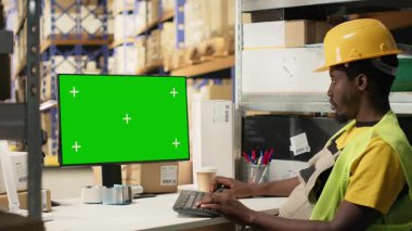 Afrika kökenli Amerikalı depo görevlisi krom ekranlı iş akışını yönetiyor, büyük depolama rafları ve rafları etrafında çalışıyor. Tatmin merkezi kargo ve e-ticareti güvence altına alır. Kamera A.
