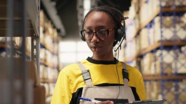 Lojistik merkezde müşteri hizmetlerine cevap veren siyahi kadın çalışanlar paketler için sipariş takibi, yanlış adres sorununu çözme ve nakliye detaylarını güncellemede yardımcı oluyorlar. Yardım hattı. Kamera B.