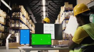 Büyük dağıtım merkezi çalışanı kargo detaylarını münferit ekran ile onaylıyor, e-ticaret tamamlama merkezinde sipariş işlemleriyle uğraşıyor. Büyük işletmeler endüstriyel faaliyetler yapıyor. Kamera A.