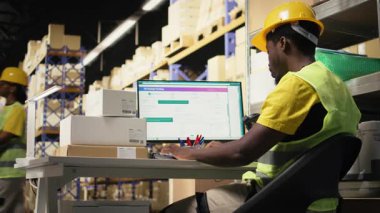 Depo çalışanı, havayolu fatura etiketlerinin izlenmesi ve e-ticaret perakende sektörü için ithalat ihracat operasyonlarının güvence altına alınması ile sipariş kaydı yapıyor. Adam sıra gereğince çalışır. Kamera A.