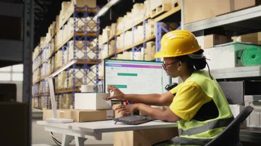 Barkodları uygulayan ve tarayan siyah işçiler kargo kutularındaki etiketleri yakalar, dağıtımdan önce malları ve sevkiyat detaylarını kaydeder. Depodaki takip numaralarında tarayıcı kullanılıyor. Kamera A.