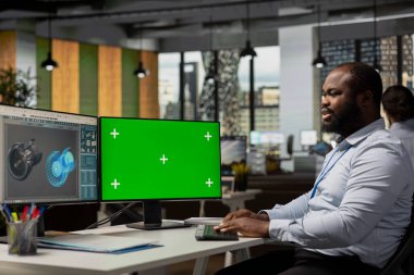İşçi, enerji tasarrufu ve düşük maliyetler için krom anahtar bilgisayardaki türbin verilerini inceliyor. Türbin çevresel etkisini değerlendirmek için izole ekran bilgisayarı kullanarak görevdeki sürdürülebilirlik uzmanı