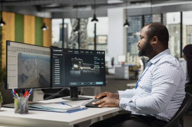 Ofisteki mühendis türbin mekaniği ve yel değirmeni çiftliği planlarını analiz etmek için çift monitör düzeneği kullanıyor. Araştırmacı türbin bileşenlerini yüksek verimlilik ve düşük çevresel etki için kalibre eder