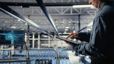 Sunucu odası çalışanı sistem sağlığını izlemek için tabletteki veri tabletlerini kontrol ediyor. Sistem yöneticisi veri merkezinin iş hedefleri ve müşteri ihtiyaçları olan kamera A 'yı karşıladığından emin olmak için grafikleri gözden geçirir