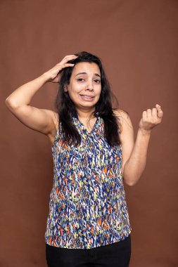 Elleri başının üstünde bir kadın, bir şey hatırlamaya çalışıyor, unutkan bir anı ifade ediyor. Gündelik kıyafetli güzel bir kadın, izole edilmiş arka planda dikilirken şaşırmış görünüyor..