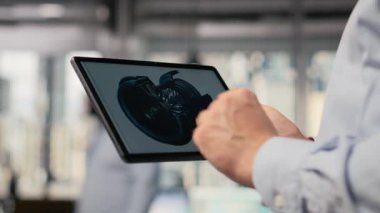 Rüzgâr türbini sürdürülebilir yapmak ve karbon ayak izini azaltmak için CAD uygulamasını tablet üzerinde kullanarak mühendisi kapat. Dokunmatik ekran cihazını araklayan Ar-Ge uzmanı, çevre dostu yel değirmeni parçalarına bakıyor, kamera B