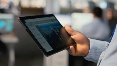 Rüzgâr türbini CAD tasarımı üzerinde çalışmak için tablet kullanarak sürdürülebilir enerji araştırması yaparak, ofisteki mühendisi kapat. İşçi cihaz üzerinde rüzgar enerjisi jeneratörünün dijital modellemesini yapıyor, kamera B