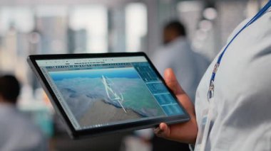 Yeşil enerji araştırmalarında kullanılan fütüristik rüzgar türbini tasarımı üzerinde çalışan mühendise yakın plan. İşçi rüzgar VAWT enerji üreteci donanımını yükseltmek için dijital modelleme tableti uygulaması kullanıyor