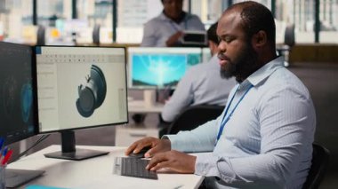 Bilgisayar üzerinde karbon ayak izini azaltmak için rüzgar türbini tasarımını optimize etmek için CAD programı kullanan teknisyen. Ar-Ge çalışanı gelişmiş malzemeleri çevre dostu yel değirmeni bileşenleri için test ediyor, kamera B