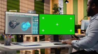 Modern ofisteki yenilenebilir enerji mühendisi yeşil ekran bilgisayar kullanarak rüzgar türbini teknolojisini geliştiriyor, güç üretimini optimize etmek için yeni malzemeler ve tasarımlar uyguluyor, kamera B