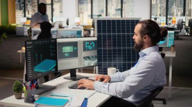 Gülümseyen sürdürülebilirlik uzmanı temiz enerji çözümleri geliştirir, güneş panelleri tasarlar. Ofisteki neşeli mühendis yenilenebilir enerji üretimini optimize etmek için rüzgar türbini çiftlikleri simülasyonu yapıyor. Kamera A