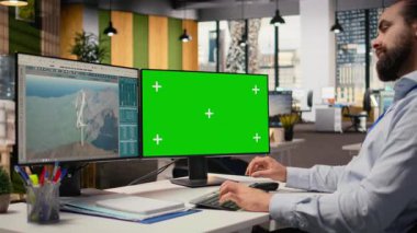 Temiz enerji üretimi için tasarlanmış yeşil ekran bilgisayarda fütüristik rüzgar türbini konsepti üzerinde çalışan mühendis. Ofisteki adam VAWT 'nin son teknoloji ürünü kamera A' yı araştırmak için model bilgisayar kullanıyor.