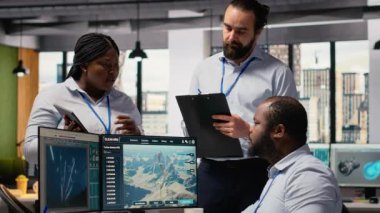 Mühendislerden oluşan bir ekip daha fazla yeşil enerji üretmek için elektrik şebekesi ve rüzgar çiftliği planını optimize etmek için beyin fırtınası yapıyor. Ar-Ge çalışanları elektrik hatları ve fütüristik rüzgar türbini simülasyonu, kamera B