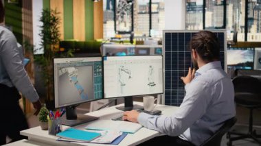 Sürdürülebilirlik uzmanı güneş paneli montajı için üretim hatları tasarlamak için bilgisayar üzerinde CAD programı kullanır. İşçi, güneş pillerini geliştirmek için simülasyon araçları çalıştırıyor, temiz enerjinin yayılmasını hızlandırıyor, kamera A