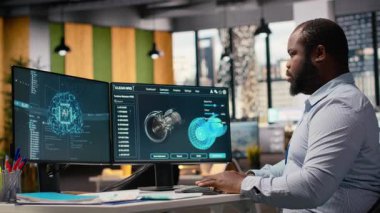 Ofisteki mühendis yapay zeka kullanarak rüzgar türbini bileşeni CAD tasarımı üzerinde çalışıyor. Afrika kökenli Amerikalı adam yapay zeka, kamera B kullanarak rüzgar enerjisi jeneratörünün dijital modellemesini yapıyor.