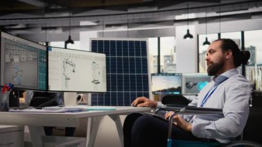 Tekerlekli sandalyedeki engelli Ar-Ge araştırmacısı güneş enerjisi sistemleri okuyor. Belden aşağısı felçli çalışanlar fotovoltaik karbon ayak izini geliştirmek için çalışıyorlar. Kamera A