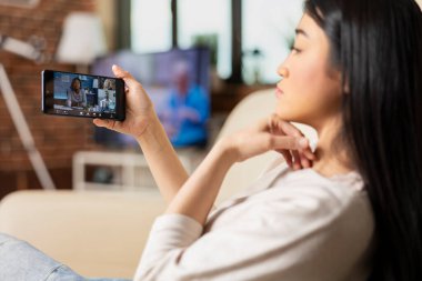 Genç bayan serbest çalışan çok ırklı bir ekiple grup video görüşmesine katılıyor. Sanal konferans için akıllı telefonu kullanan serbest meslek sahibi kadın, çeşitli iş adamlarıyla iletişim kuruyor..