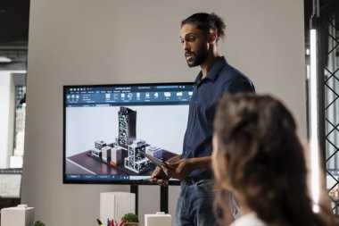 Ortadoğulu şehir planlamacısı, inşaat tasarım fikirleri ve şehir planlaması hakkında brifinge ev sahipliği yaparak iş arkadaşlarına büyük planları sunuyor. Gayrimenkul geliştirme üzerinde çalışıyorum..