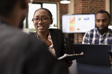 Siyahi çalışanlarla konuşan, soru soran ve yeni başlayan şirketlerin mali raporlarını inceleyen iş kadınlarına odaklan. Kadın pazarlama uzmanı iş arkadaşıyla stratejileri tartışıyor.