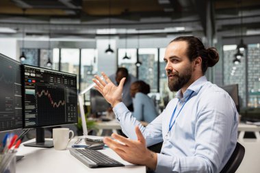 Tescilli firma ofisinde borsa verilerini analiz eden ve PC 'deki ticaret platformu panelini kullanarak alım satım işlemlerini yürüten bir tüccar. Varlık yönetimi temsilcisi bilgisayar kullanarak hisse senedi değerlerini izliyor