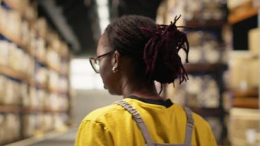 Afrika kökenli Amerikalı işçiler ticari lojistik sistemi için ürün işliyor, endüstriyel raflarla dolu bir depo alanı var. Çevrimiçi perakende satış merkezinde nakliye protokolleri. Kamera B.