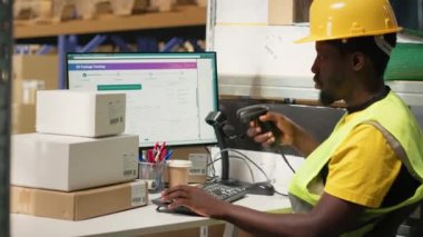 Afrikalı Amerikalı erkek çalışanlar büyük bir depoda paketleri tarıyor. Endüstriyel depo kayıtlarında havayolu faturalarını kaydediyor. Sipariş yerine getirmek için tarayıcı kullanılıyor. Kamera B.