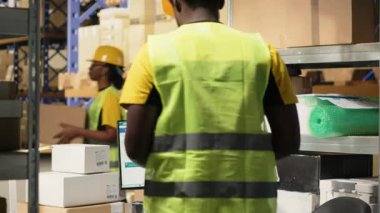 Depo çalışanı envanterde kaydedilecek nakliye etiketlerini tarıyor, depo yönetim sistemindeki kayıtları güncelliyor. Sanayi bölgesinde e-ticaret dağıtım operasyonları. Kamera B.