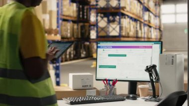 Lojistik merkezde çalışan Afrikalı Amerikalı bir kadın. Bilgisayarla ilgili bilgileri takip ediyor. Teslimat güzergahını ve diğer sevkiyat detaylarını gerçek zamanlı olarak güncelliyor. Çevrimiçi siparişler için paket durumunu takip ediyorum. Kamera B.