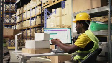 İşçi etiketleri uyguluyor ve barkod etiketlerindeki takip bilgi numaralarını tarıyor, karton kutulara nakliye etiketleri kaydediyor. Tamamlama Merkezi personeli paket durumu ve teslimat güzergahı gösteriyor. Kamera A.