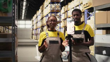 Siyah e-ticaret ekibi bir depo nakliye bölgesinde kayıt yapıyor. Endüstriyel operasyonlar için reklam yaratmak için ürün kullanımı, tatmin için ekspres dağıtım hizmetlerini desteklemek. Kamera A.