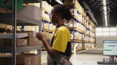 Depo katibi depo deposundaki kutulara yapışkan nakliye etiketleri yapıştırıyor, paketleri yanlış takip numaralarıyla etiketliyor ve kusursuz hızlı teslimat ve sipariş işlemlerinden emin oluyor. Kamera A.