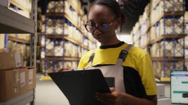 Afro-Amerikalı kadın, lojistik sistem, dağıtım merkezi, raflar ve nakliye protokolleri için ticari verileri inceliyor. Perakende satış ve tedarik zinciri. Kamera A.