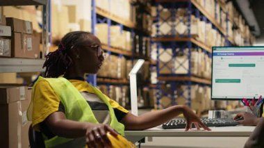 Afro-Amerikan depo memurları paket izleme yazılımının paket durumunu izliyor, müşterileri güncellemek için e-ticaret lojistiği ve nakliye rotasını yönetiyor. Sipariş yerine getirilmesi. Kamera B.