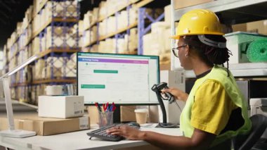 Siyah depo asistanı takip bilgilerini tarayıcı ile kaydeder, dağıtım işleminden önce paket hazırlıklarıyla ilgilenir. Kutulardaki sevkiyat detayları için barkodları tarıyorum. Kamera A.