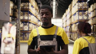 Depoda canlı yayında işbirliği yapan iş arkadaşları parsel işleme ve işleme sergiliyorlar. Afrikalı Amerikalı işçiler ticari bir kampanya için ürünler sunuyorlar. Kamera A.