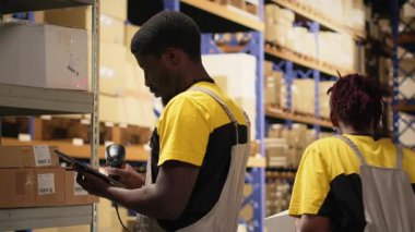 Teslimat merkezi çalışanı envantere kayıt olmak için nakliye etiketlerini tarıyor, tabletteki yönetim sistemindeki kayıtları güncelliyor. Sanayi bölgesinde e-ticaret perakende dağıtım operasyonları. Kamera B.