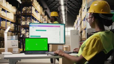 Kadın depo görevlisi ekranda krom anahtarın yanındaki etiketleri kontrol ediyor, depoda endüstriyel depolama raflarıyla çalışıyor. Dağıtım ve e-ticaret ile tatmin merkezi ilgilenir. Kamera A.