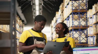 Zenci işçiler büyük bir depoda sevkiyat için mal hazırlıyorlar, envanterleri kontrol ediyorlar ve kargo dağıtımını yönetiyorlar. Lojistik siparişleri için paketleri sıralıyorum. Kamera B.