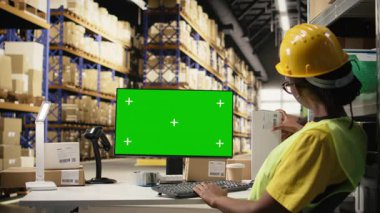 Kadın çalışan, fotokopi masasının yanındaki kutuların üzerindeki havayolu fatura etiketlerini onaylıyor. Dağıtım işlemleri için büyük askıları olan endüstriyel depoda yelek giyiyor. İnternetten alışveriş. Kamera A.