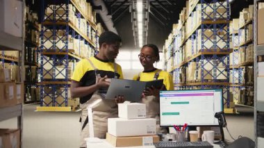 Zenci işçiler büyük bir depoda sevkiyat için mal hazırlıyorlar, envanterleri kontrol ediyorlar ve kargo dağıtımını yönetiyorlar. Lojistik siparişleri için paketleri sıralıyorum. Kamera A.